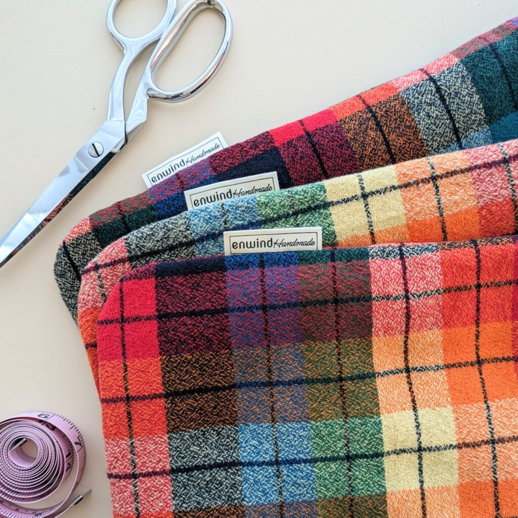 Handmade rainbow plaid hot water bottle cover with sewing scissors and measuring tape